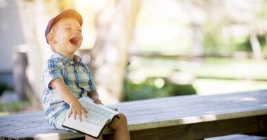 boy sitting on a table holding a book and laughing